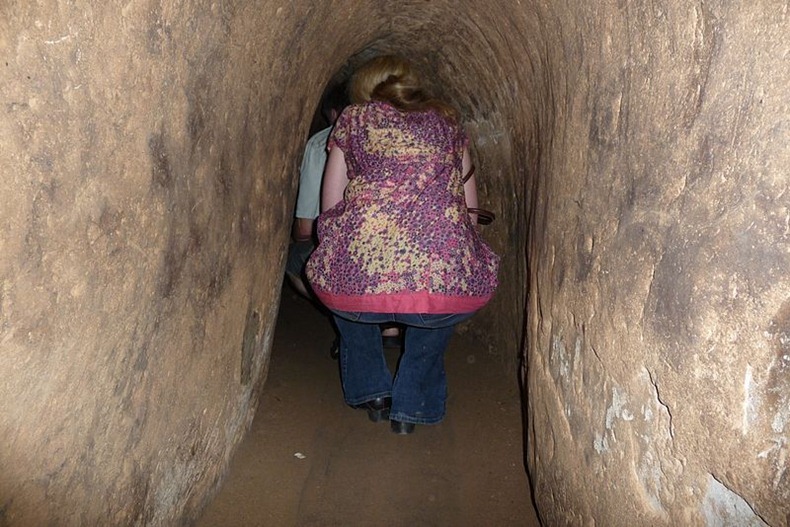 Tourists navigate the dark and narrow tunnels